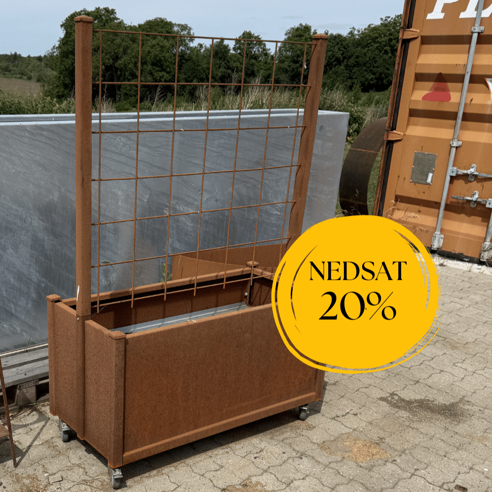 Rektangulær plantekasse i cortenstål med indbygget espalier ovenpå og hjul under kassen, fotograferet udendørs ved en byggeplads
